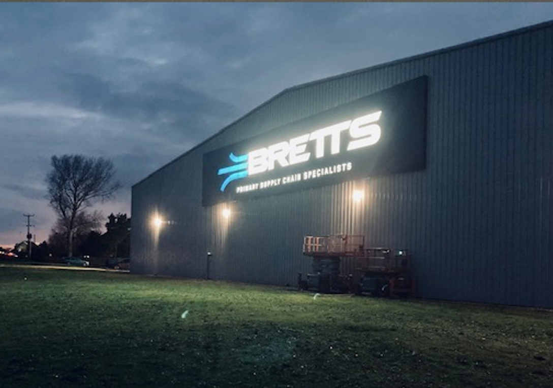 Large illuminated sign for Bretts Transport night view
