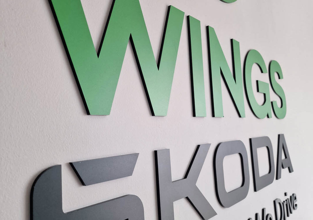Laser cut Wings Skoda letters and logo applied onto a white office wall 