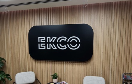 An illuminated black and white reception sign which reads ECKO with two chairs below it