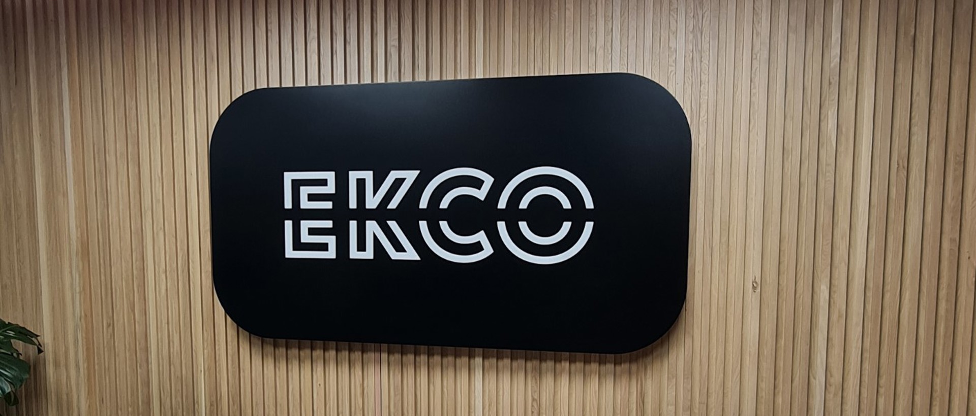 An illuminated black and white reception sign which reads ECKO with two chairs below it